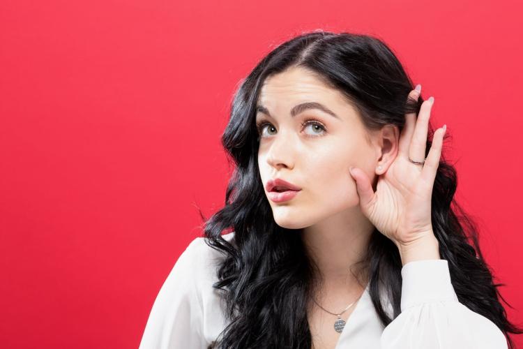 Femme avec la main sur l'oreille pour entendre