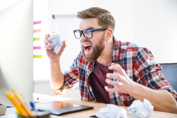Homme qui s'énerve devant son ordinateur